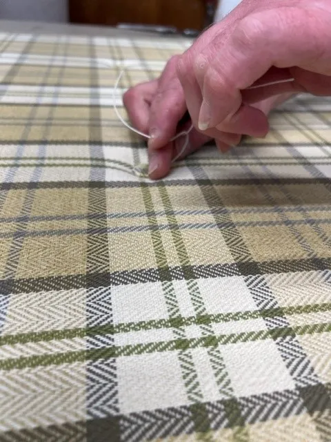 Tying a new button on a caravan cushion in the workshop