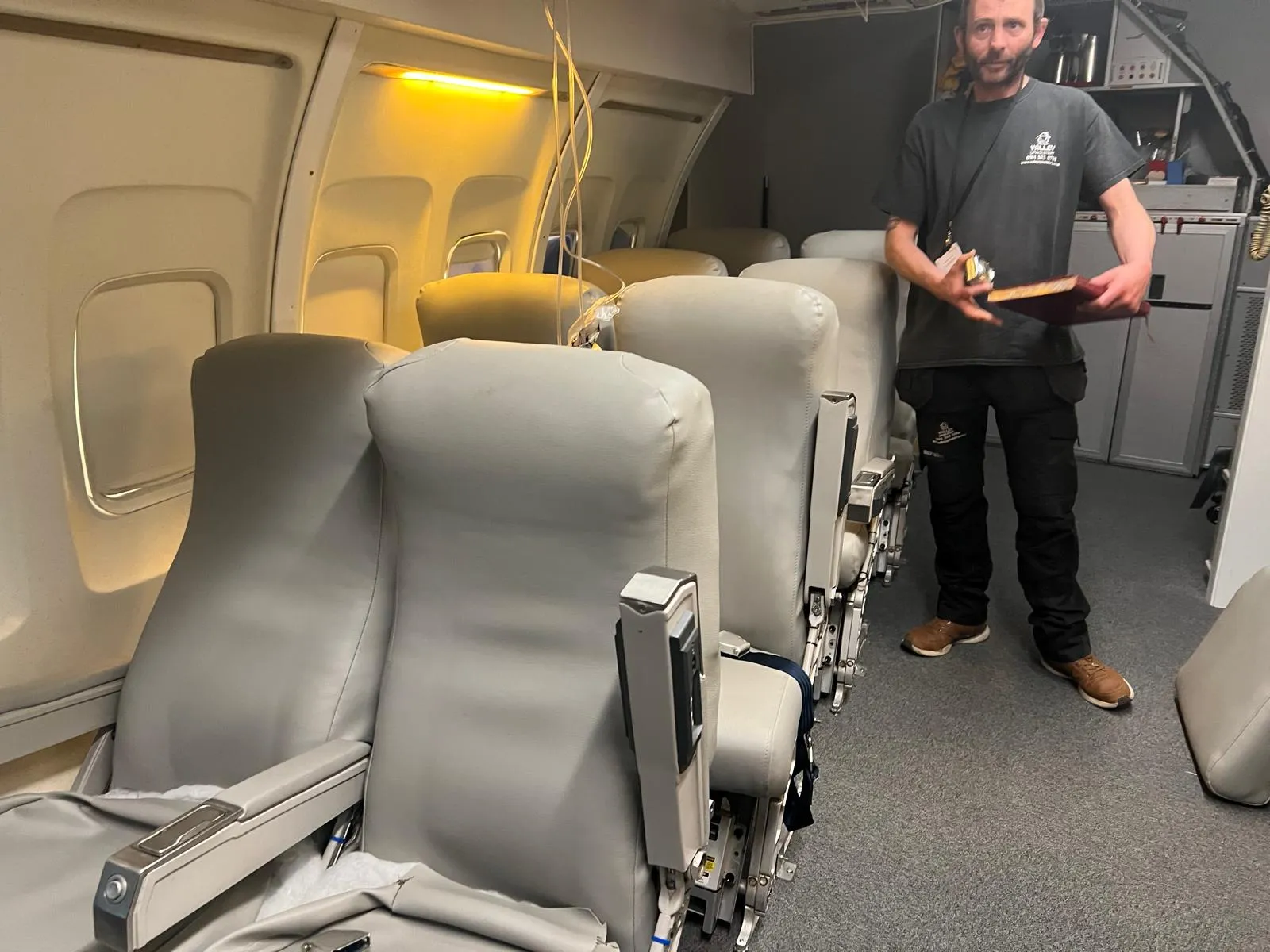 Cabin crew training mock-up mid-recover: bare seat shells and foam in place, Valley craftsman on site with templates