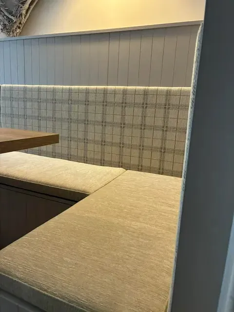 Close-up of the cream chenille seat cushion meeting the tartan-check back panel along the corner banquette