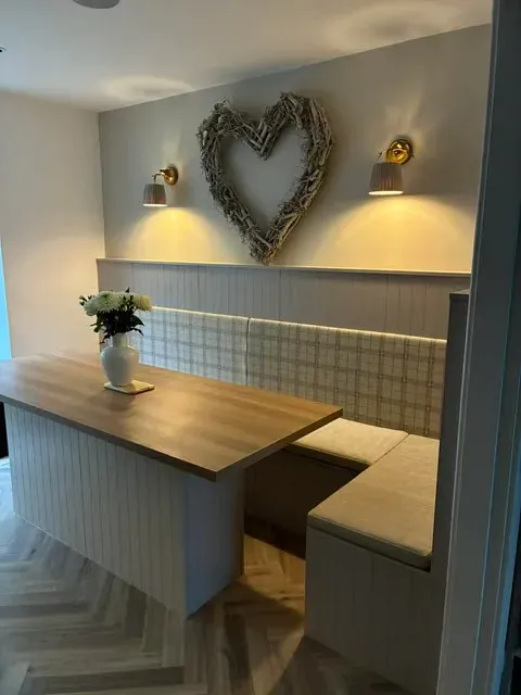 Bespoke L-shaped kitchen banquette with cream chenille seat cushions and tartan-check back panels, completed through a commercial trade account.