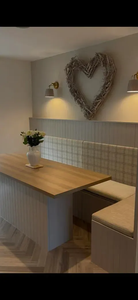 Vertical view of the kitchen banquette showing the corner bench, table, panelled island and herringbone flooring