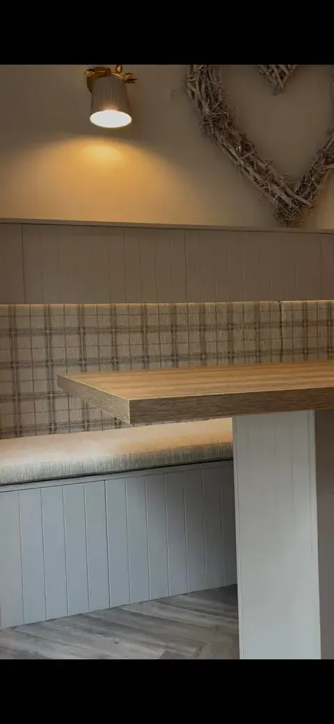 Banquette back panel under a brass wall sconce with the wooden bar top and panelled island in view