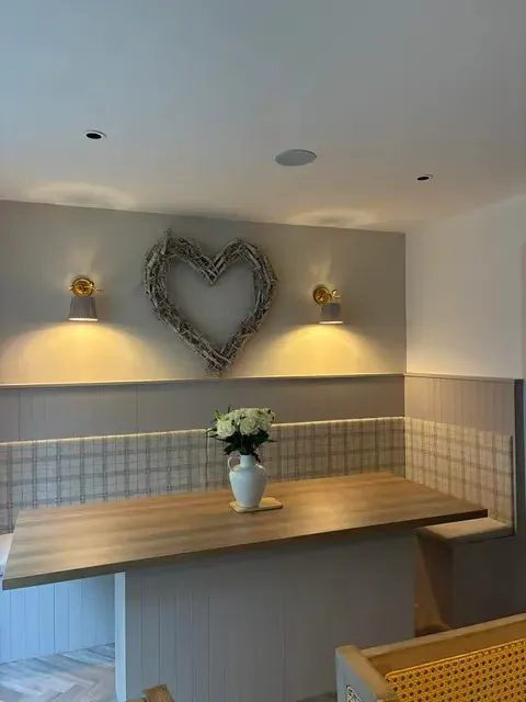 Wide view of kitchen breakfast nook with banquette seating, wall sconces and heart wreath