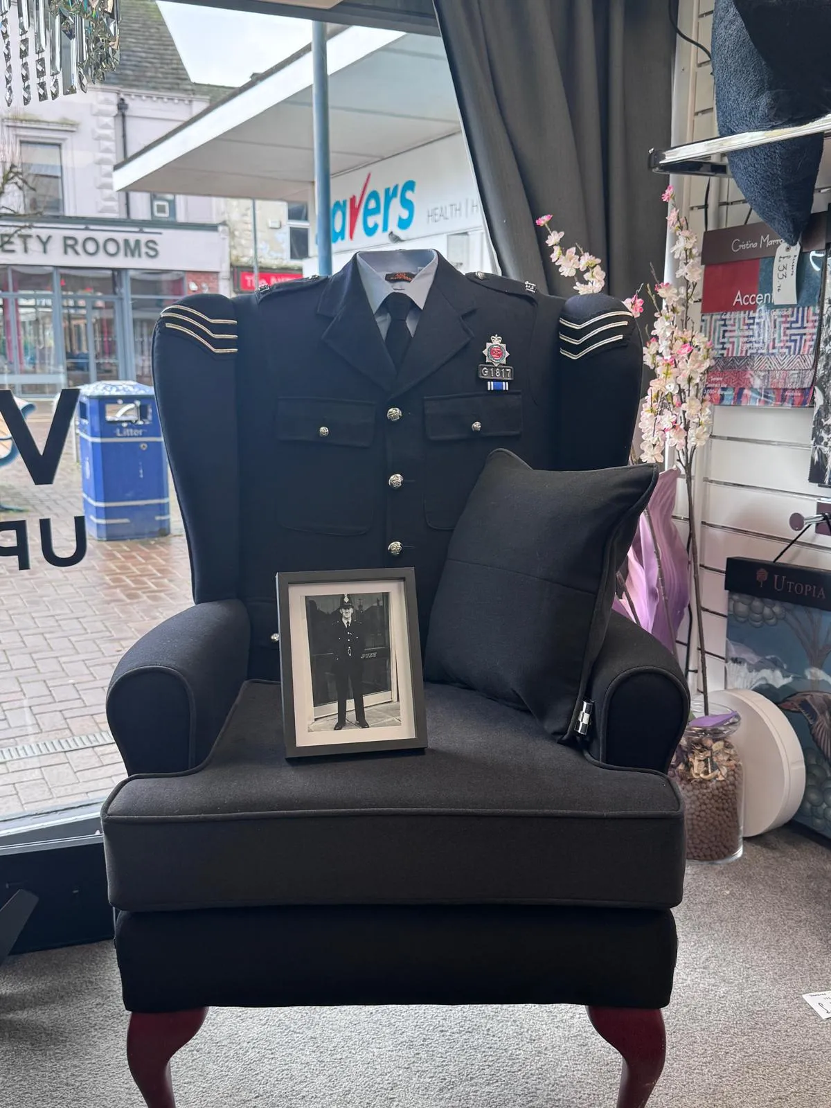 Wingback armchair upholstered in Greater Manchester Police service uniform wool, with a framed photograph of the customer's late father resting on the seat.