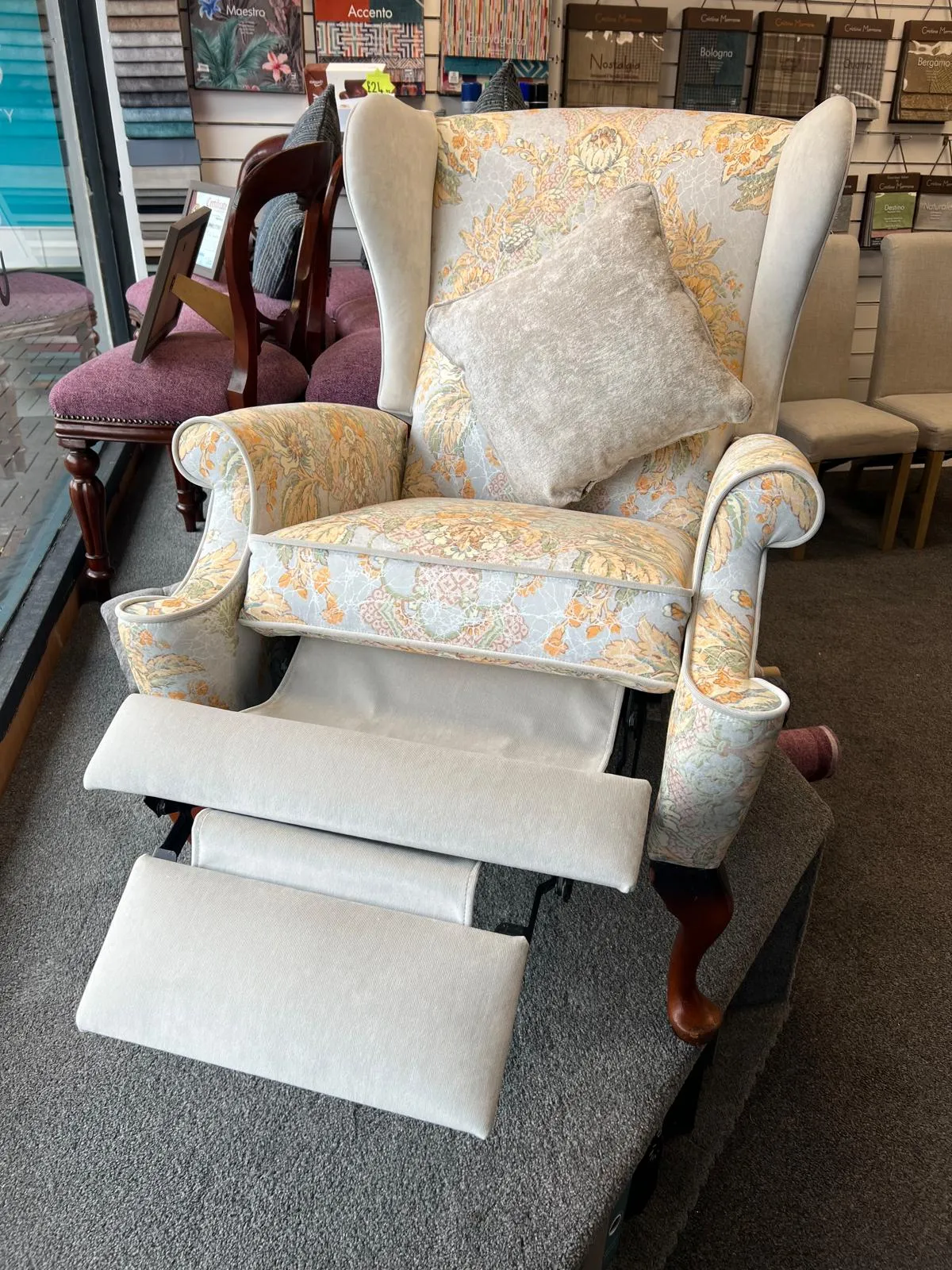 Wingback riser recliner reupholstered in floral fabric with plain footrest, Stalybridge showroom