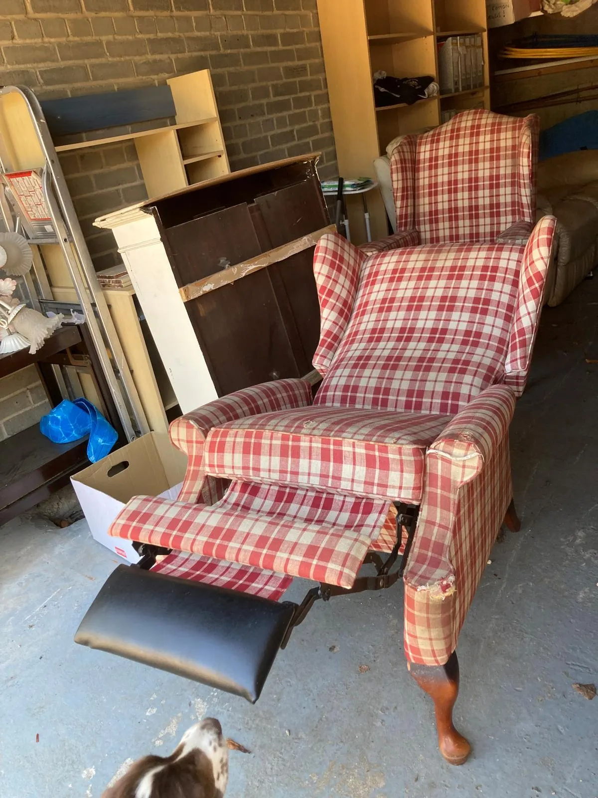 Worn red-and-cream plaid riser recliner before recover, footrest extended and cover split on the arms