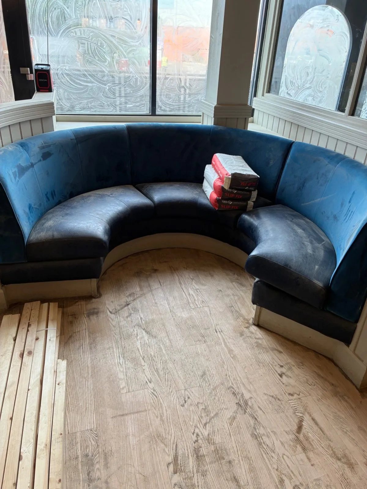 Curved restaurant corner booth with its seat bases lifted out during a recover on site