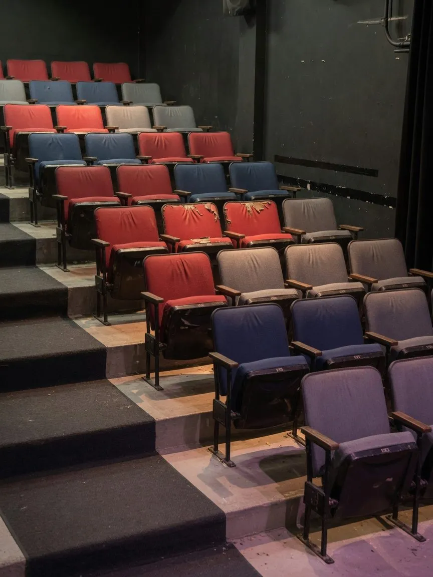 Small theatre with raked tip-up seats in mixed red, navy and grey fabric
