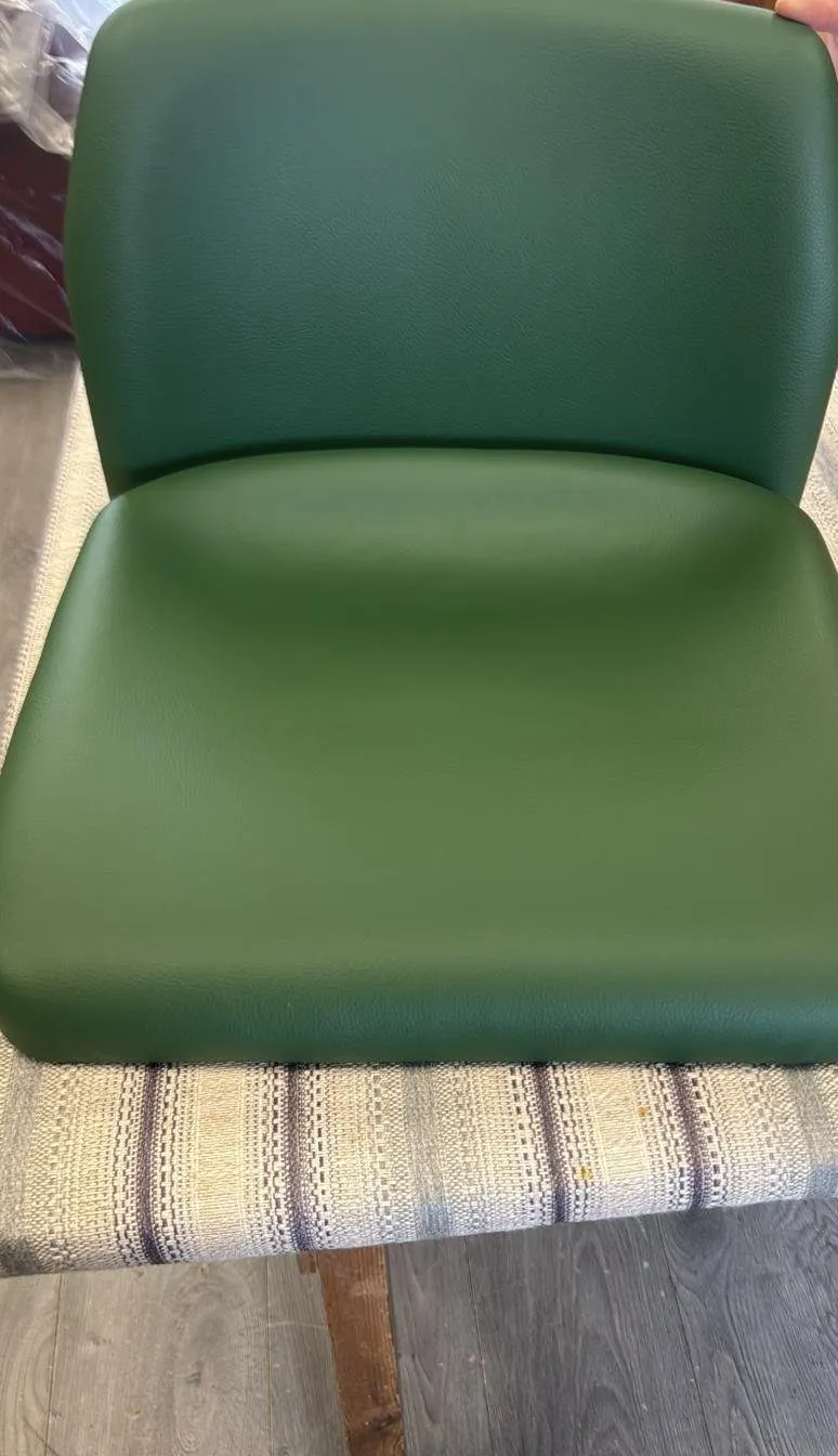 Stadium seat shell covered in dark green leather-look vinyl