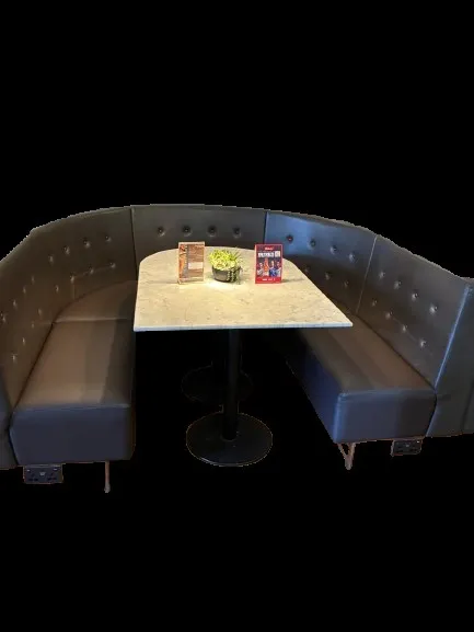 Curved deep-buttoned booth in dark brown faux leather around a marble-topped table